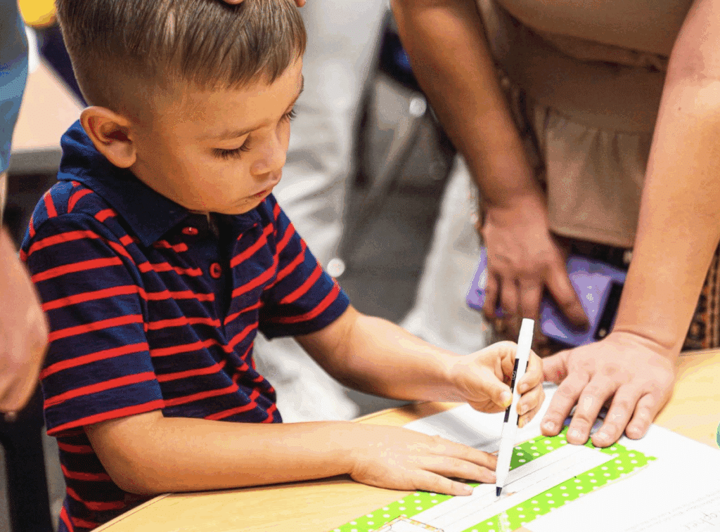 Boy writing with a marker in classroom setting